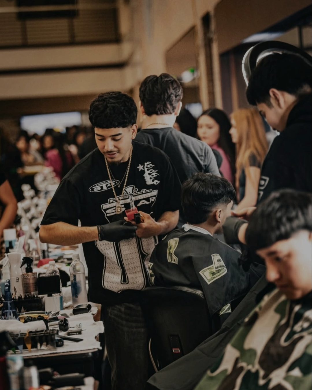 Diego cutting on the floor at a Houston barber event, crowd behind him